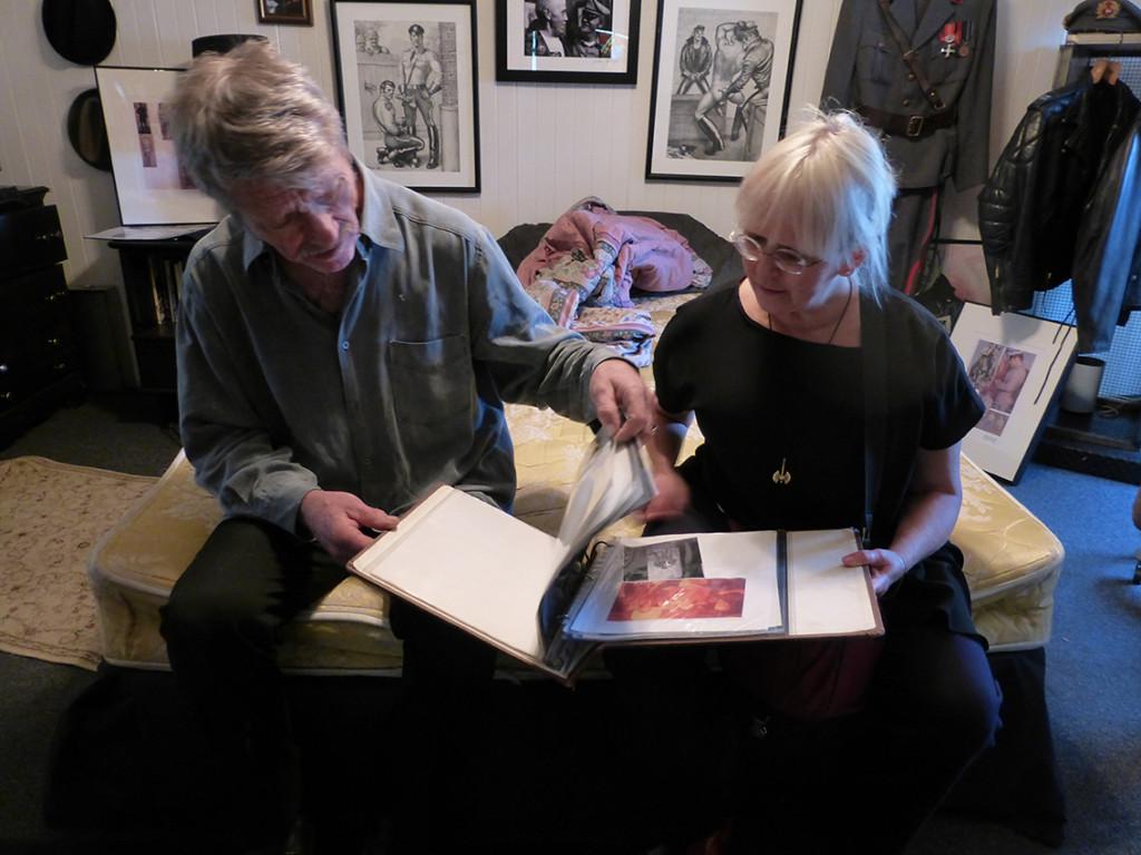 Istun Durk Dehnerin kanssa Touko Laaksosen sängyllä Toukon ullakkohuoneessa. Durk näyttää minulle vanhoja Laaksosen valokuvakansiota. Taustalla on Laaksosen kehystettyjä piirroksia ja asepuku sekä nahkatakki.