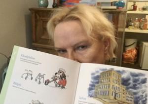 Nainen, jolla on vakava ilme, piilottaa kasvonsa puolittain avatun kirjan taakse. Kirjassa kerrotaan humoristisesti vammaistermeistä.