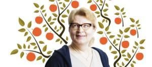 Silmälasipäinen vaalea nainen hymyilee vasempaan yläviistoon, taustalla piirretty omenapuu punaisine omenoineen.